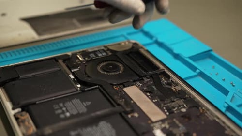 Skilled Technician Repairing Laptop Motherboard Disassembling Electronic Components with Screwdriver