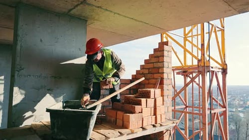 Construction Worker Building Brick Wall A Construction Worker Wearing a Red Hard Hat and Yellow