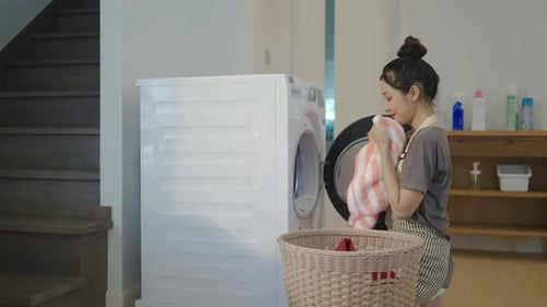 Woman Unloads Laundry from Washing Machine into Basket