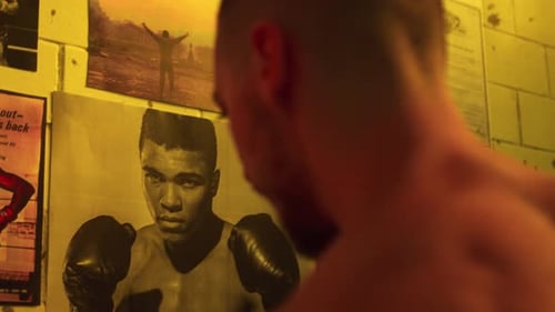 A boxer gazes at legendary posters