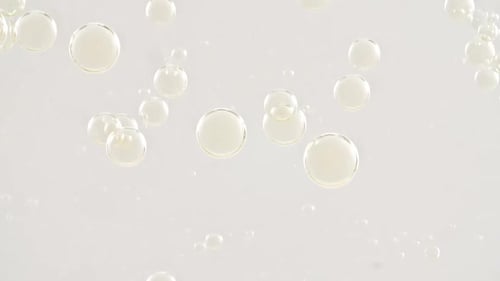 Makroaufnahme von goldenen Luftblasen in klarem Wasser, die auf weißem Hintergrund aufsteigen, Körperpflege-Kosmetik