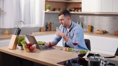 Young Man Works and Eats in Modern Kitchen