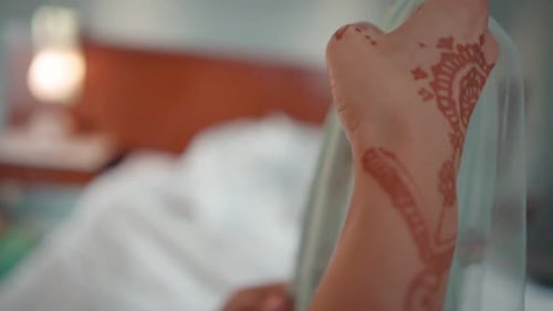 Manos de una mujer con henna doblando una pieza de ropa. Manos de mujer con tatuaje natural de henna.