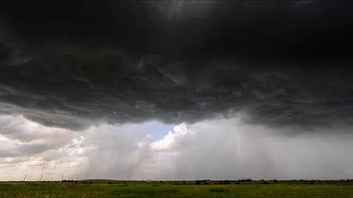 Dramatic Storm Clouds Above Expansive Green Field