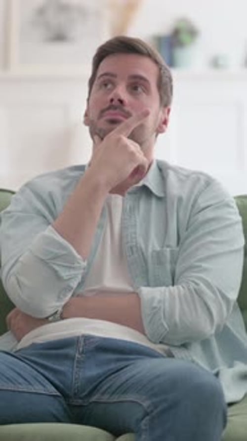 Young Man Thinking while Sitting on Sofa, Vertical Video