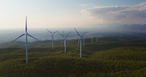 Aerial shot of wind mills rotating by the force of the wind and generating renewable energy in a g