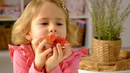Little Girl Eating Gummy Bears from Glass Dish