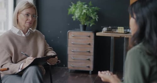 Two Young Women Psychologist and Client Talking Discussing Issue Talking Indoors in Office