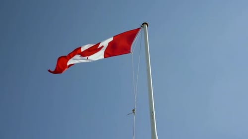 Canadian Flag Waving Against Blue Sky
