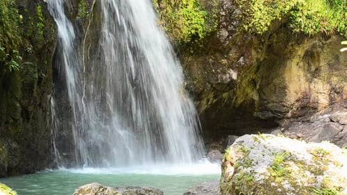 Large amounts of fresh mountain water falling into a turquoise basin underneath. Narrow angle view o