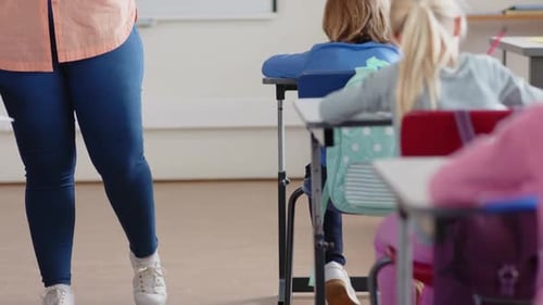 In school, female teacher using tablet while assisting student in classroom