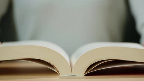 Hands Turning Pages in Open Book