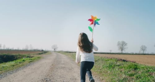 Girl Runs with Pinwheel on Rural Farm Road