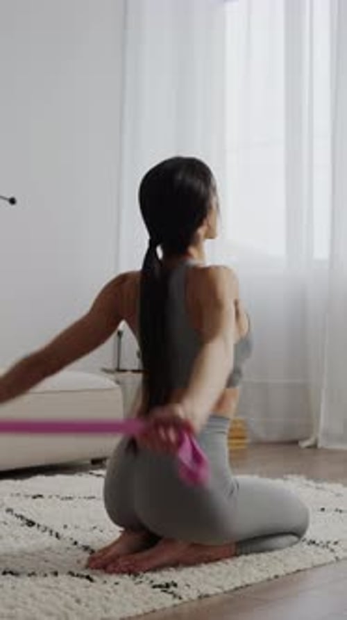 Athletic Woman Doing Seated Exercise with Pink Resistance Band