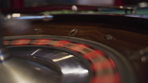A spinning roulette wheel in a casino with the ball just dropped down and bouncing out of the wheel