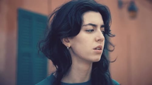 Contemplative Young Adult with Wavy Hair Outdoors