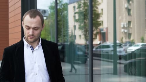 Confident businessman walking to work communicating on his smartphone in slow motion