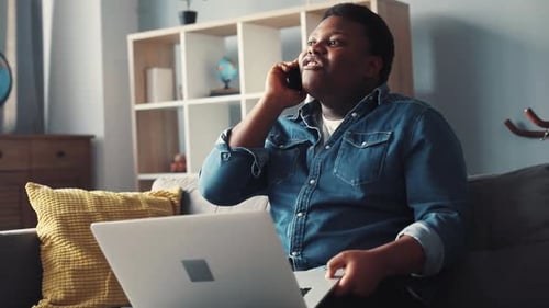 Man with Laptop Talking on Phone at Home