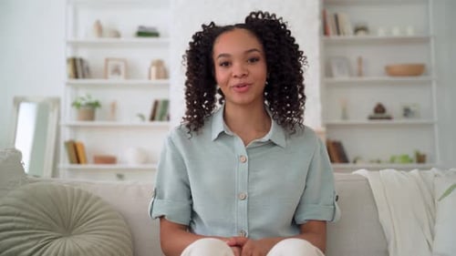 Smiling Woman Sits on Sofa Talking to Camera