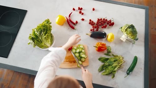 Vegetable Preparation: Person Slicing Cucumber in Kitchen