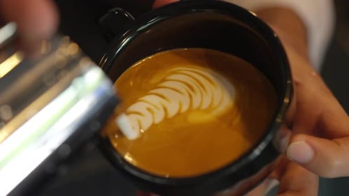 4K Close up of Barista hand pouring froth milk in espresso coffee making coffee latte in coffee cup.
