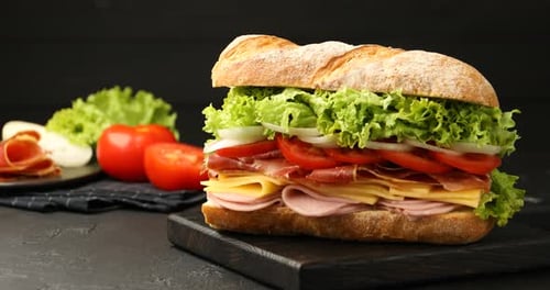 Delicious sandwich on wooden board with fresh ingredients