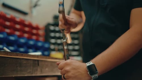 Male hands hammering in slow motion in workshop for custom golf club fitting