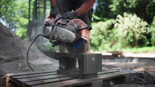 Construction Worker Man Using Concrete Saw to Cut Concrete Brick at Outdoor Construction Site