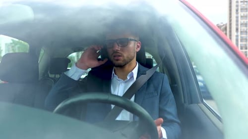 Man Talking on Phone in Car is Distressed