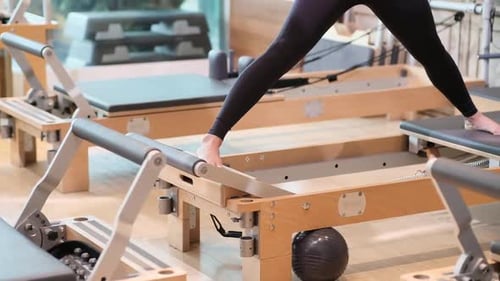 Woman Exercising on Pilates Reformer Machine