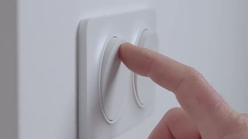 Hand Pressing Light Switch to Turn on Lighting
