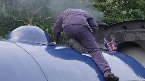 Engineer checking steam release ontop of steam train