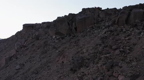 Rising up above cliff to see vast desert landscape. Drone wide shot.