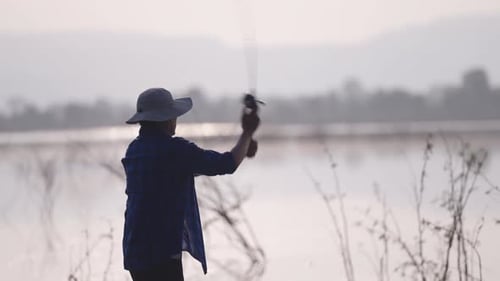 Ein junger Mann fischt am Fluss. Vor dem Hintergrund des blauen Himmels, in der Natur, der Fischer