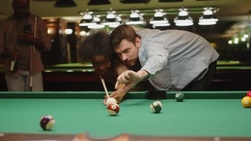Friends playing pool together in a brightly lit hall