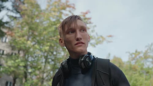 Man outside with headphones, looking at something