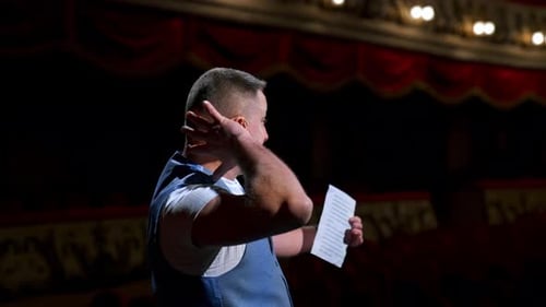 Man entertainer, presenter or actor on stage. Active gestures of throwing to the auditorium.