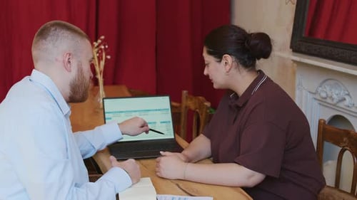 Business Partners Briefing Documents at Table with Laptop in Cafe