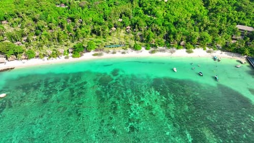 Sandy beach shore with beautiful resort surrounded by clear sea water.