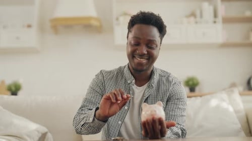 Young Black Man Putting Coin in Piggy Bank at Home Portrait of Happy Student Save Money Financial