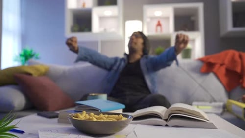 Man Reads Book and Stretches on Couch