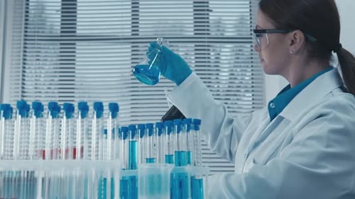 Woman Scientist Stirring Flask in Laboratory