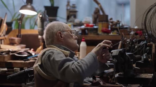 Senior Elderly Master Jeweler in Wheelchair Works in a Workshop