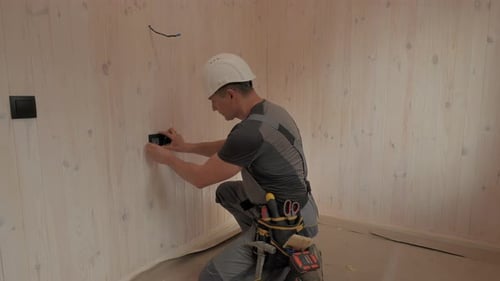 Electrician Installing Electrical Outlet in New Home Construction