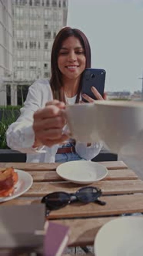 Young Woman Making a Coffee Toast with Friend at Sidewalk Cafe