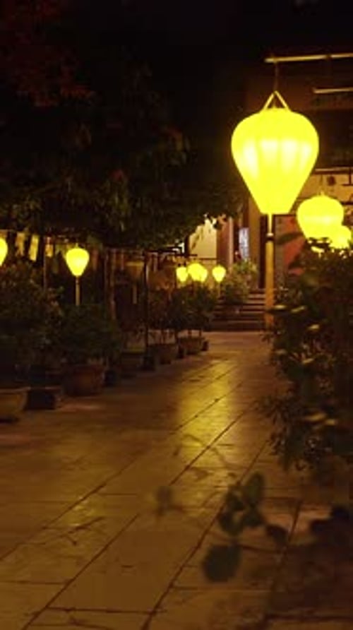 Vidéo verticale. Sentier éclairé par une lanterne menant à l'entrée du temple la nuit, capturé avec un grand angle
et
