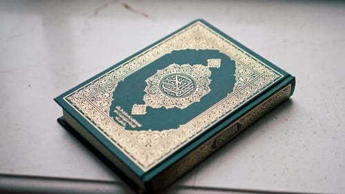 Der Heilige Koran der islamischen Religion liegt geschlossen vor Beginn des Gebets auf dem Tisch eines Muslims.