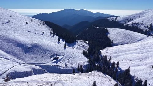 Aerial view of snowy mountain cabin with breathtaking distant peaks