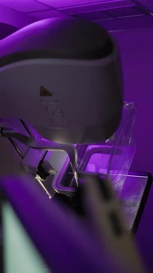 Shot in motion showing mammography equipment activated with a violet background light inside a