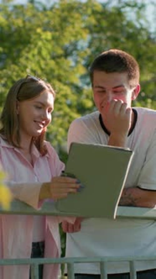 Young adults looking at tablet outside in park